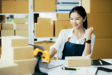 Genç Asyalı kadınlar müşterilerden gelen yeni siparişten sonra mutlu olurlar. Asyalı bir kadının online mağazasının satışındaki başarısının sürpriz ve şok edici yüzü. Çevrimiçi satış. Çevrimiçi Alışveriş