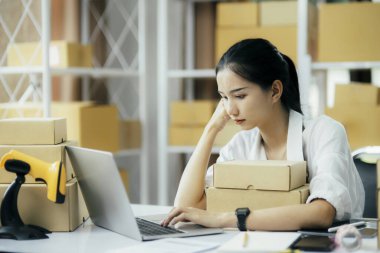 Asyalı girişimci çevrimiçi işletme sahibi iş problemleri konusunda yorgun ve stresli ve ilk ürün parasının kaybedilmesi, merkez ofisteki bilgisayardan çevrimiçi siparişi kontrol ettiğinde satılamaz.
