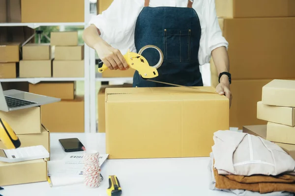 Close up online business owner prepares product for delivery to the customer. Online entrepreneur using scotch tape to seal parcel box. small business owner, SME concept.