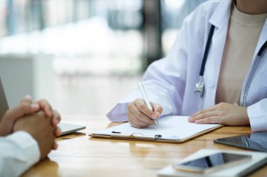Doktor ve hasta. Doktor muayenehanesinde reçeteli hastaya teşhis koymayı ve tedavi planlarını tartışmayı bitirin. Tıbbi ve sağlık hizmetleri kavramı.