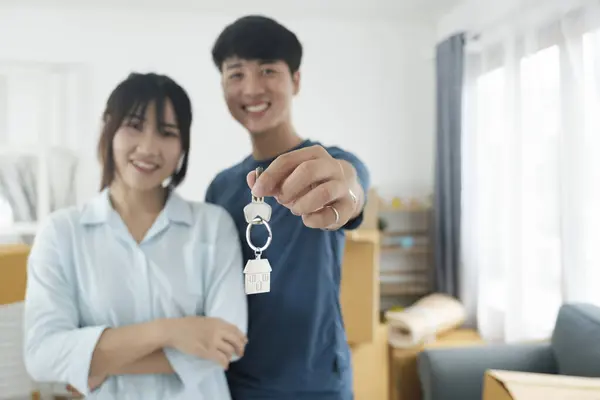 Happy young couple buying a new house receiving the keys. House owner real estate concept.