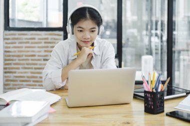 Çevrimiçi eğitim, e-öğrenme. Bilgisayar ve mobil cihaz kullanan genç bir kolaj öğrencisi. Asyalı genç öğrenci çevrimiçi öğrenim sınıfı çalışması Zoom hocası adı verilen online video eğitimi.