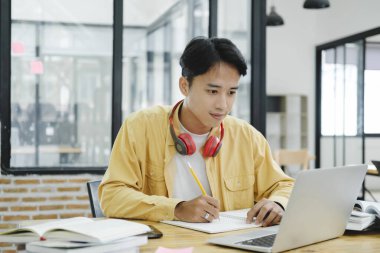 Çevrimiçi eğitim, e-öğrenme. Bilgisayar ve mobil cihaz kullanan genç bir kolaj öğrencisi. Asyalı genç öğrenci çevrimiçi öğrenim sınıfı çalışması Zoom hocası adı verilen online video eğitimi.