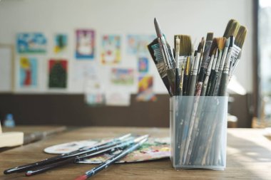 Sanatçının stüdyosundaki fırçaları boyayın. Ressam fırçaları ve boyaları sanatsal tuvale yakın plan. Retro tonlu. Seçici odak...