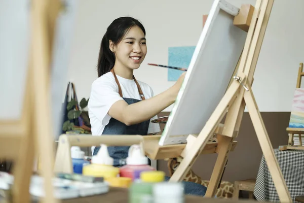 Young female artist sketches or paints her drawing on canvas in a studio workshop. A teenage girl who likes art and drawing is taking time to create her watercolors on canvas with great intention