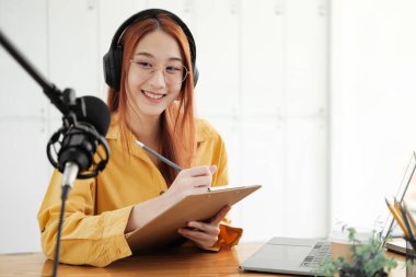 Canlı yayına ev sahipliği yapan neşeli kadın stüdyoda profesyonel mikrofon kullanarak seyircilerle iletişim kuruyor..