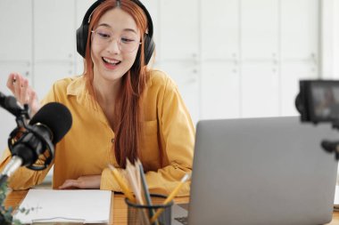 Canlı yayına ev sahipliği yapan neşeli kadın stüdyoda profesyonel mikrofon kullanarak seyircilerle iletişim kuruyor..