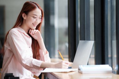 Bilgisayar ve mobil cihaz kullanan genç bir kolaj öğrencisi. Eğitim ve çevrimiçi öğrenim.