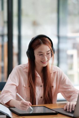 Bilgisayar ve mobil cihaz kullanan genç bir kolaj öğrencisi. Eğitim ve çevrimiçi öğrenim.