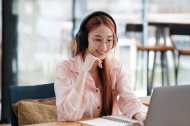 Bilgisayar ve mobil cihaz kullanan genç bir kolaj öğrencisi. Eğitim ve çevrimiçi öğrenim.