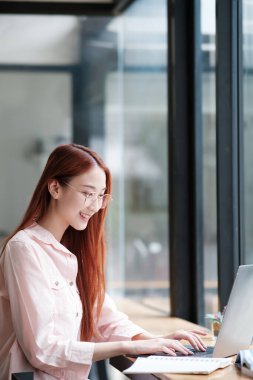 Bilgisayar ve mobil cihaz kullanan genç bir kolaj öğrencisi. Eğitim ve çevrimiçi öğrenim.