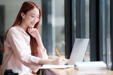 Bilgisayar ve mobil cihaz kullanan genç bir kolaj öğrencisi. Eğitim ve çevrimiçi öğrenim.