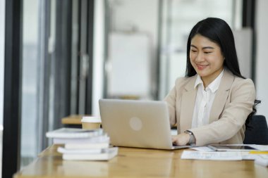 Elinde parlak bir ofis ortamında dizüstü bilgisayarla çalışan odaklanmış bir iş kadını...
