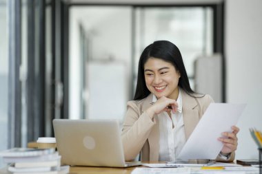 Elinde parlak bir ofis ortamında dizüstü bilgisayarla çalışan odaklanmış bir iş kadını...