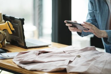 Çevrimiçi satış mağazası, küçük işletme girişimcisi Asyalı genç bir kadın reklam amaçlı dijital kamerayla akıllı cep telefonu kullanıyor internet pazarında satış postası satıyor..