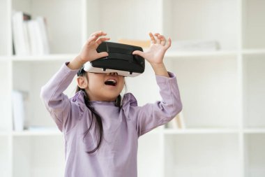 İlkokul çağındaki bir kız heyecan ile öğrenme deneyimini geliştirmek için sanal gerçeklik kulaklığı kullanıyor. VR ürünleri için pazarlama, eğitim teknolojisi içeriği.