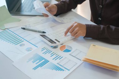 Bir muhasebeci, yatırım için kullanılan mali bütçeyi yönetmek için fatura geliri ve yatırım bilgilerini hesaplamak için bir hesap makinesi kullanıyor