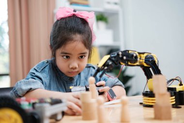Bir ilkokul öğrencisi uzaktan kumandayla bir robotik kolu çalıştırmaya odaklanarak BTMM eğitimini iş başında gösteriyor..