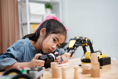 Bir ilkokul öğrencisi uzaktan kumandayla bir robotik kolu çalıştırmaya odaklanarak BTMM eğitimini iş başında gösteriyor..