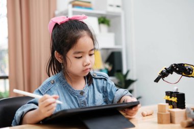 Bir ilkokul öğrencisi uzaktan kumandayla bir robotik kolu çalıştırmaya odaklanarak BTMM eğitimini iş başında gösteriyor..