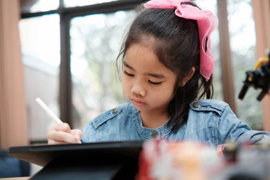 Bir ilkokul öğrencisi uzaktan kumandayla bir robotik kolu çalıştırmaya odaklanarak BTMM eğitimini iş başında gösteriyor..