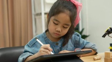 Eğitimde teknolojiyi kucaklayan, dijital tablet üzerine resim çizmek için stilus kalem kullanan, kot giymiş konsantre genç bir kız..