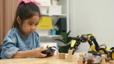 Bir ilkokul öğrencisi uzaktan kumandayla bir robotik kolu çalıştırmaya odaklanarak BTMM eğitimini iş başında gösteriyor..