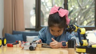 BTMM sınıfındaki genç bir Asyalı kız oyuncak bir arabayı uzaktan kontrol etmek için akıllı telefon uygulaması kullanıyor..