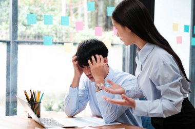 Bir meslektaşı stresli ve bunalmış görünürken, diğeri bir iş tartışması sırasında açıklama veya çözüm sunuyor.