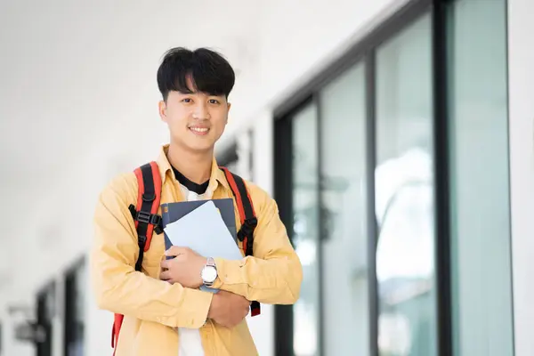 一个大学生站在学校的走廊上 拿着课本 面带微笑 准备一天的学习 免版税图库图片