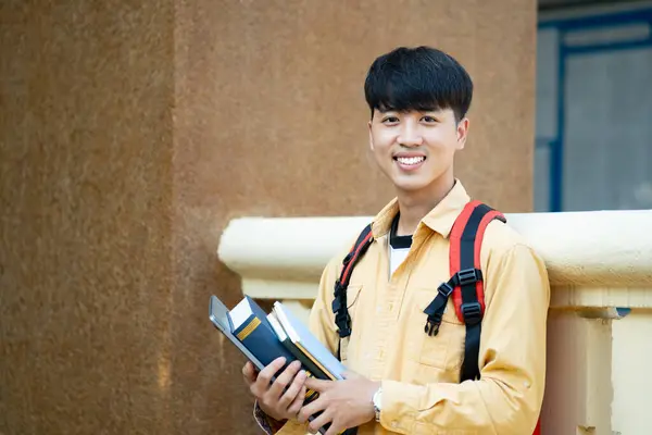 Dizüstü Bilgisayar Kitaplar Taşıyan Memnun Bir Üniversite Öğrencisi Kampüs Boyunca Stok Fotoğraf