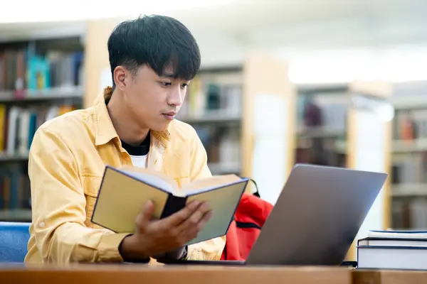 Genç Bir Adam Bir Dizüstü Bilgisayar Bir Kitapla Masada Oturuyor Telifsiz Stok Imajlar
