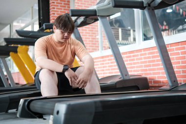 Aşırı egzersizden sonra kilolu bir adam spor salonunda oturup dinleniyor..