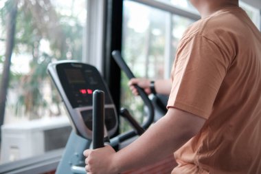 Spor salonunda bisiklete binen bir adam gülümsüyor. İyimserlik ve motivasyon kavramı, adam egzersizden ve sağlığıyla ilgilenmekten zevk alıyor.