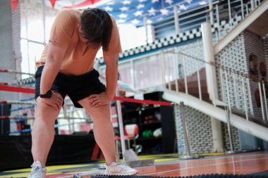 Bronz gömlekli bir adam dizleri bükülmüş şekilde diz çöküyor. O ayaklarına bakıyor.