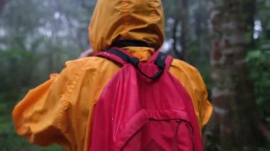 Sarı ceket giyen ve kırmızı sırt çantası taşıyan biri bir ormanda yürüyor. Sahne kasvetli ve gizemli, ağaçlara karşı insan silueti ve ıslak, bulutlu gökyüzü