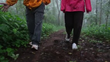 Ormanda yürüyen iki kişi. Biri sarı ceket giyiyor, diğeri de pembe ceket giyiyor.