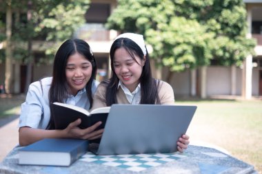 Bir grup üniversite öğrencisi kampüste birlikte okuyorlar, bir dizüstü bilgisayar ve kitapları ortak bir ortamda kullanıyorlar..