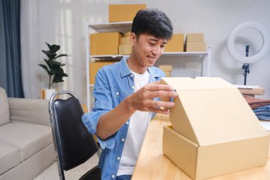 Çevrimiçi dükkanda çalışan adam. Dostum, küçük işletmelerin sahibi kutuya koyup teslimat için hazırlıyor..