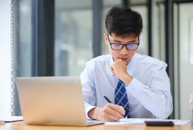 Bir işadamı hisse senedi performansı, yatırım sonuçları veya vergi ve bütçe bilgilerini gösteren grafiklerden elde edilen risk, yatırım ve pazar verilerini analiz eder.