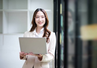 Bir iş kadını verileri incelerken dizüstü bilgisayar kullanıyor ve arka planda yapışkan notlar görülüyor. Görüntü veri analizi, beyin fırtınası fikirleri ve profesyonel bir iş planlamasını temsil ediyor.