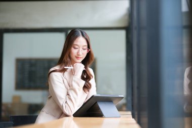 Bir iş kadını not almak, veri analizi, e-imzalar ve tasarım için tablet ve dijital kalem kullanır. Görüntü, üretkenlik, verimlilik ve mesleki görevler için modern araçları vurgular.