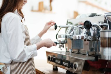 Kahveyi hazırlamak için espresso makinesi kullanan bir barista hassasiyet ve uzmanlık gösteriyor. Sahne, modern bir kafe işinde gerekli olan profesyonellik ve ayrıntılara dikkat çekiyor.