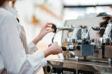 Kahve makinesiyle kafede kahve hazırlayan bir garson ya da kafe çalışanı. Sahne, iş ortamında hayati önem taşıyan adanmışlık, hassasiyet ve müşteri odaklı hizmeti vurguluyor.