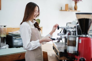 Kahveyi hazırlamak için espresso makinesi kullanan bir barista hassasiyet ve uzmanlık gösteriyor. Sahne, modern bir kafe işinde gerekli olan profesyonellik ve ayrıntılara dikkat çekiyor.