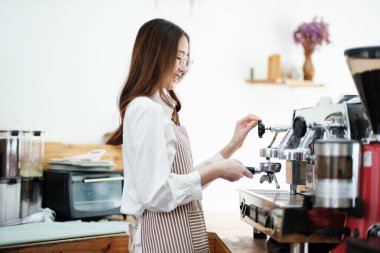 Kahveyi hazırlamak için espresso makinesi kullanan bir barista hassasiyet ve uzmanlık gösteriyor. Sahne, modern bir kafe işinde gerekli olan profesyonellik ve ayrıntılara dikkat çekiyor.