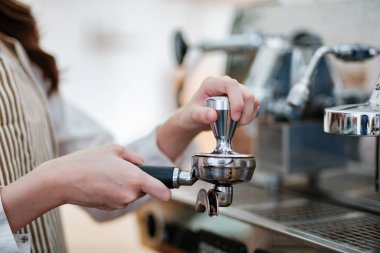 Kahve telvesini iskele filtresine dolduran bir barista hassasiyet ve beceri gösteriyor. Sahne, bir kafe işletmesindeki profesyonellik ve ayrıntılara dikkat çekiyor.