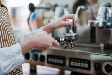 Kahve telvesini iskele filtresine dolduran bir barista hassasiyet ve beceri gösteriyor. Sahne, bir kafe işletmesindeki profesyonellik ve ayrıntılara dikkat çekiyor.