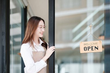 Bir kafe çalışanı, bir mağaza çalışanı ya da müşterileri karşılamak için kapıyı açan bir mal sahibi. Sahne, bir kafe ortamında samimiyet, konukseverlik ve profesyonelliğin sergilendiği yeni bir iş gününün başlangıcını vurguluyor..