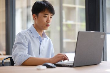 Odaklanmış bir iş danışmanı dizüstü bilgisayar üzerinde çalışıyor, mali verileri ve yatırım raporlarını analiz ediyor. Yoğunlaştırılmış ifadesi stratejik planlama, muhasebe veya piyasa araştırması öneriyor..